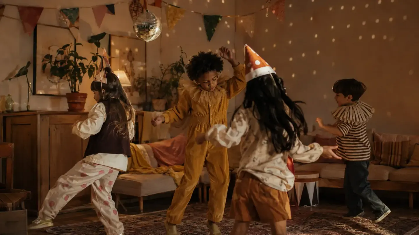 kinderen dansen in een verduisterde kamer met gekleurde lichtjes en slingers